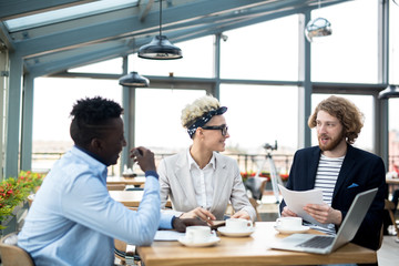 Confident employee making report for their colleagues during meeting in cafe and sharing his ideas