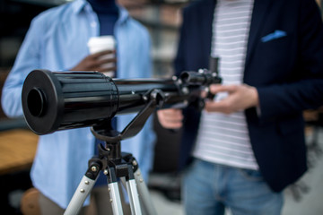 Professional telescope on tripod and two young men going to use it