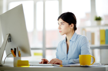 Serious businesswoman concentrating on network or watching webcast in computer