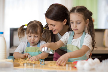 Obraz premium happy family mother and kids are preparing the dough, bake cookies in the kitchen