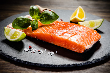 Fresh raw salmon fish served on black stone on wooden table