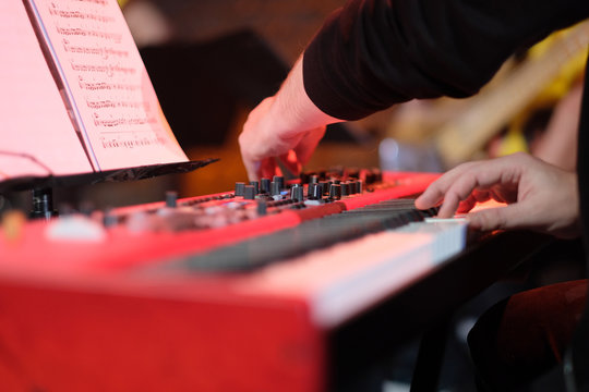A musician on an electric piano plays live music at a concert in an orchestra