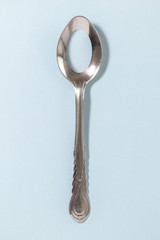 Holey spoon isolated on blue background. Dieting and food intake control.