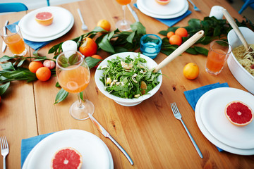 Vegetarian salad, juice in glasses, fruit decorations and grapefruit halves on plates served for guests