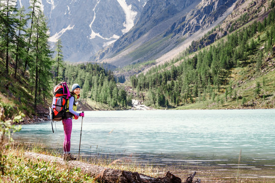 girl hiker standing on a rock and looking at the lake in Altai mountains