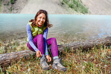 a tourist woman ties up her shoelaces on trekking boots, outdoor footwear concept