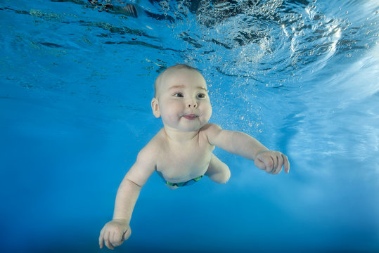 little boy learns to swim underwater in the pool