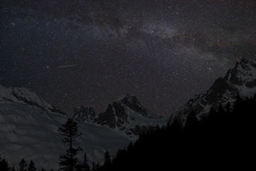 Fototapeta na wymiar Mountain peaks in the background of the milky way. Night landscape with starry sky