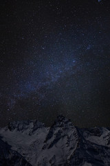 Mountain peaks in the background of the milky way. Night landscape with starry sky
