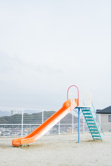 Naklejka premium A slide in the playground with nobody on it while the weather is cloudy.