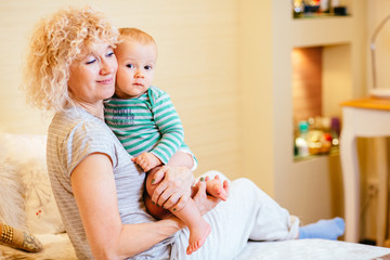 Portrait of happy grandmother with grandson embracing indoor.