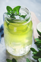 Cold lemonade mojito in a glass jar with lime and mint.