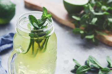 Cold lemonade mojito in a glass jar with lime and mint.