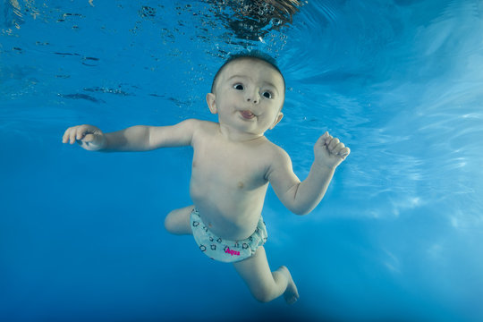 little boy learns to dive underwater in the pool
