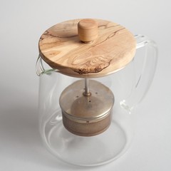 Empty glass teapot with wooden cap on light background