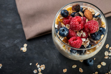 bowl of yogurt, berries and muesli on dark background
