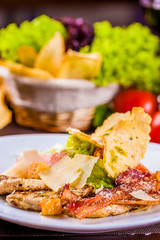Caesar salad with bacon and chicken on white plate