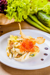 Salad with salmon and avocado on white plate