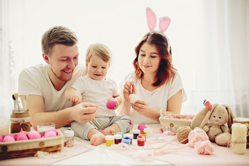 Obraz na płótnie Canvas Mother, father and daughters are painting eggs. Happy family are preparing for Easter. 