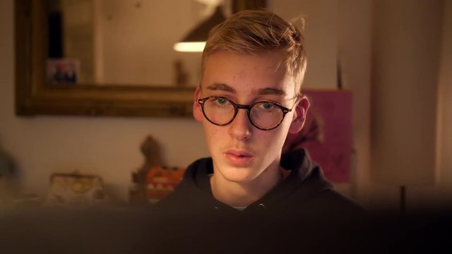 Teenage boy gaming, face looking at monitor.