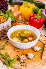 Soup with chicken meatballs, vegetable and quail eggs in white plate