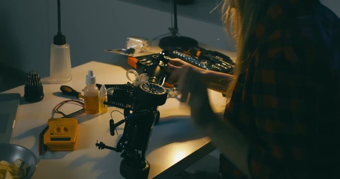 Young attractive teen girl assembling toy RC car at home in the evening. Hobby concept. 4K UHD