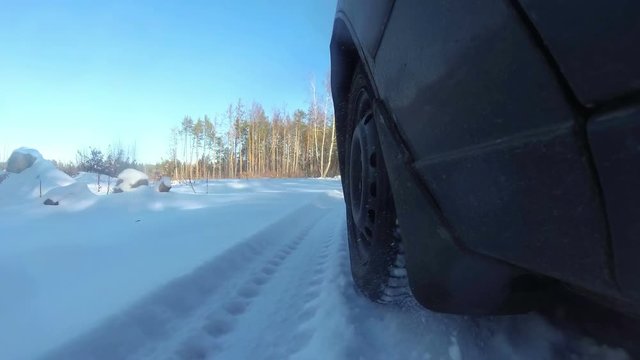 4K.Car goes on winter forest or  park. View of  wheel, POV clip