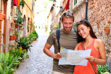 Europe travel tourists couple looking at map to find directions walking in old streets of spanish...