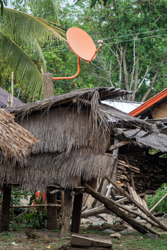 a modern satellite dish on the roof of shack in hmong village, Laos. Traditional house in the hmong tribe village.