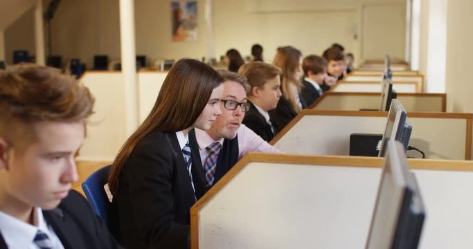 4k, A mature teacher with school children working in a large computer lab. Slow motion.