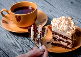 Man eating cake and drinking tea while sitting at a wooden table