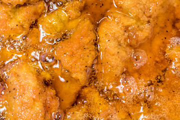 Frying the meat wrapped in breadcrumb on the pan, close up. Fried chicken in oil.