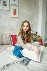 Young beautiful curly hair brunette woman in jeans on bed