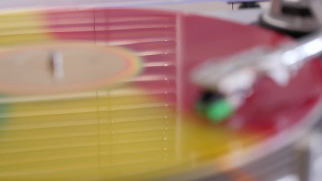 beautiful background colorful vinyl record player rotates on the turntable reflection of a window with blinds on the surface of the vinyl