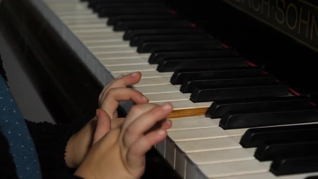 Close up of child's hands playing piano.
