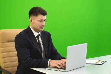 The man sit near the laptop on the green background