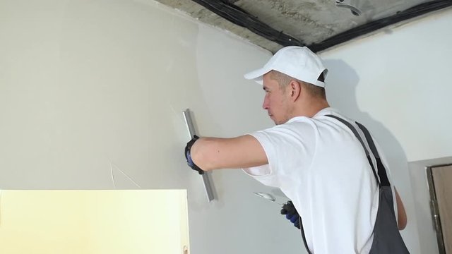 refurbishment. Worker spackling a wall with putty