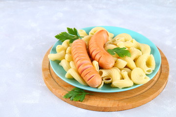 Pasta Cavatappi or Cellentani with sausages on a gray table.