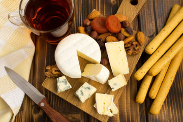 Snack  with cheeses and bread sticks on the brown  wooden background.View from above.