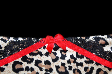 Textile detail with red ribbon bow and leopard pattern with black lace glamorous background