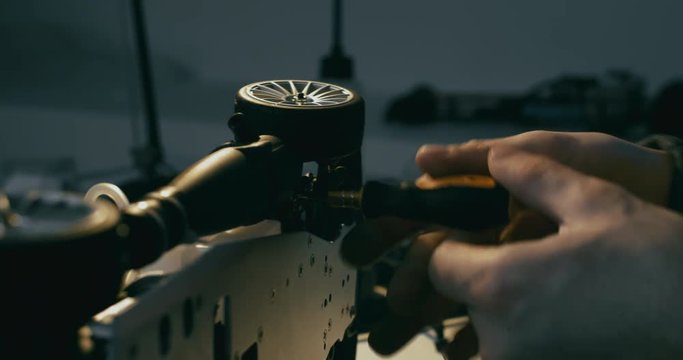 Young adult Caucasian male assembling toy RC car at home in the evening. Hobby concept. 4K UHD