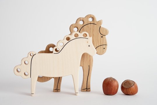 Wooden hand-made horse toy for children isolated on the white background with shadow reflection. Wooden acorn for playing with kids. Natural typical wooden toy in the shape of little horse