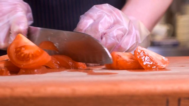 The chef in black apron cuts vegetables.