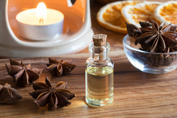A bottle of star anise essential oil with star anise on a wooden table