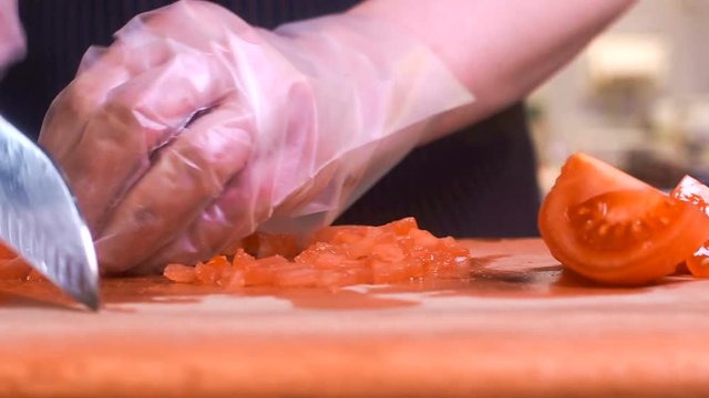The chef in black apron cuts vegetables.