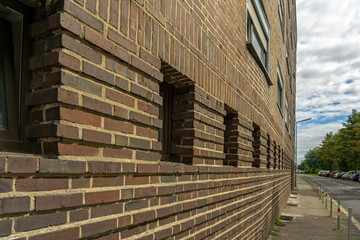 The brick wall of an old house below a cloudy summer sky