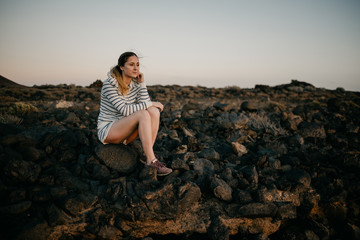 Girl sitting on the rock in the evening