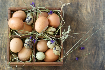 Chicken and quail eggs in a wooden box. Rustic style.