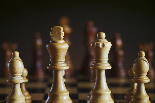 Detail of wooden white chess figures, dark background