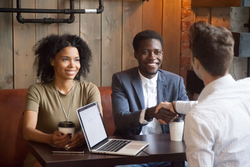 Smiling african american couple shaking hands to mortgage insurance broker, financial advisor or...